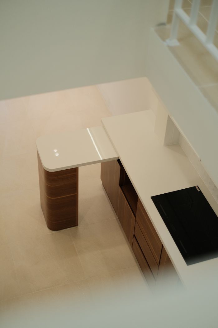 Services Aerial view of a minimalist modern kitchen with white countertops and wooden cabinets.