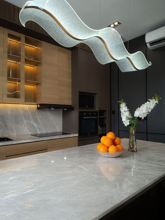 Services Luxurious modern kitchen featuring sleek lighting, marble countertop, and fresh oranges on display.